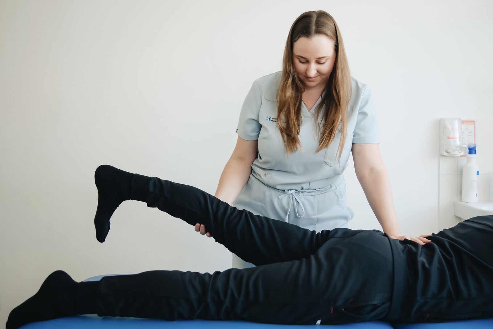 Um fisioterapeuta ajuda um paciente a alongar a perna durante uma sessão de terapia na clínica em Vilnius.